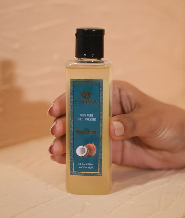 Hand holding bottle of 100% pure cold-pressed coconut oil image on padma home page