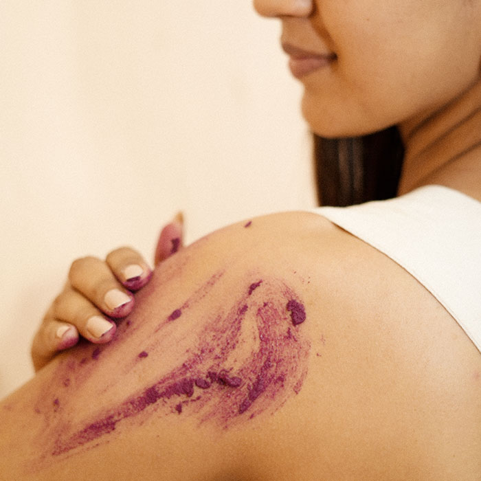 Woman applying a purple skincare product to shoulder image on padma gallery page